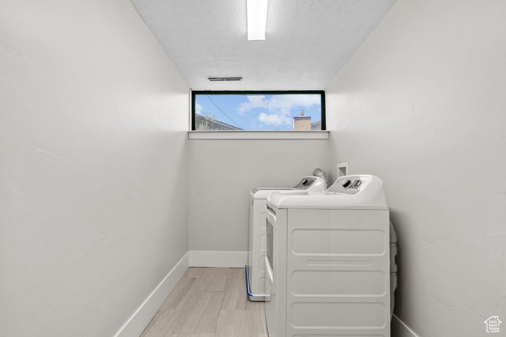 Washroom featuring separate washer and dryer, a textured ceiling, and baseboards