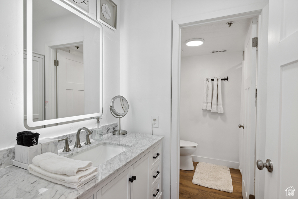 Bathroom with vanity, toilet, and wood finished floors