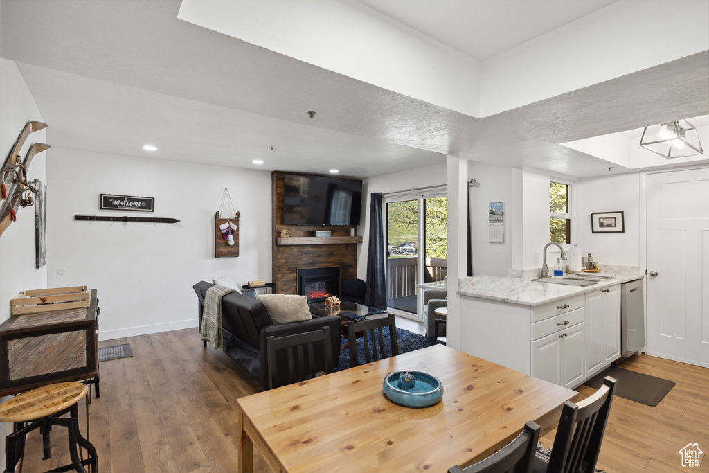 Dining room featuring light wood-style flooring, a large fireplace, recessed lighting, and baseboards