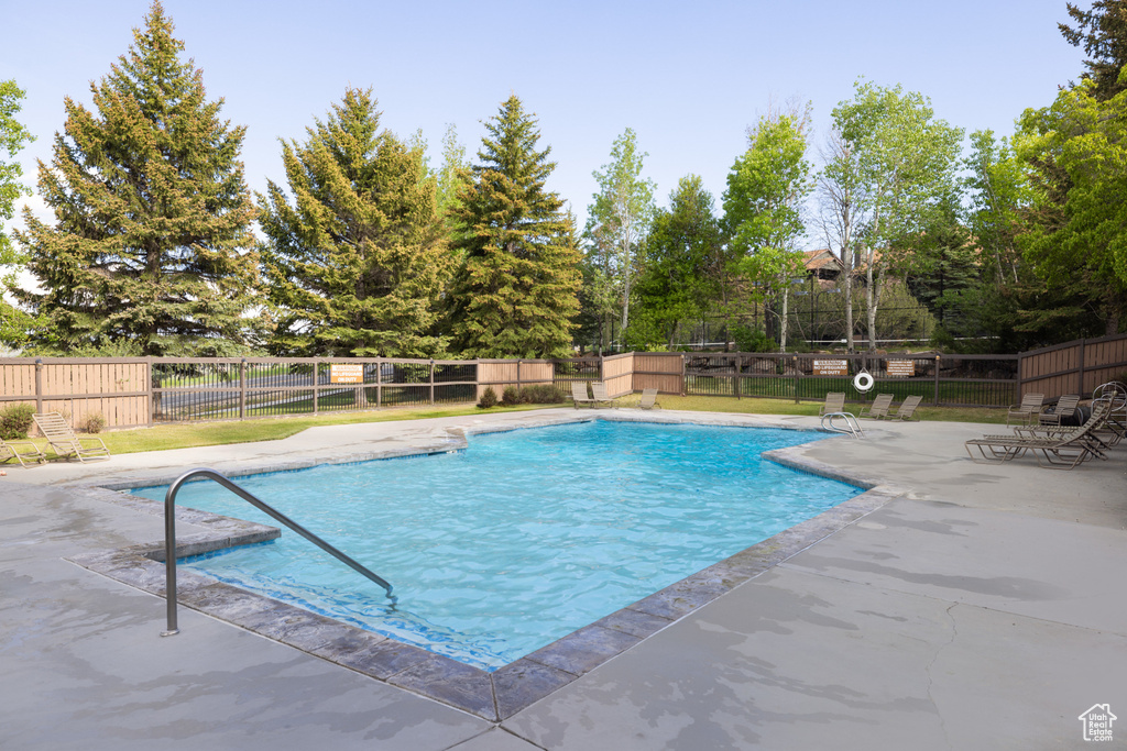 Community pool featuring a patio area and view of wooded area