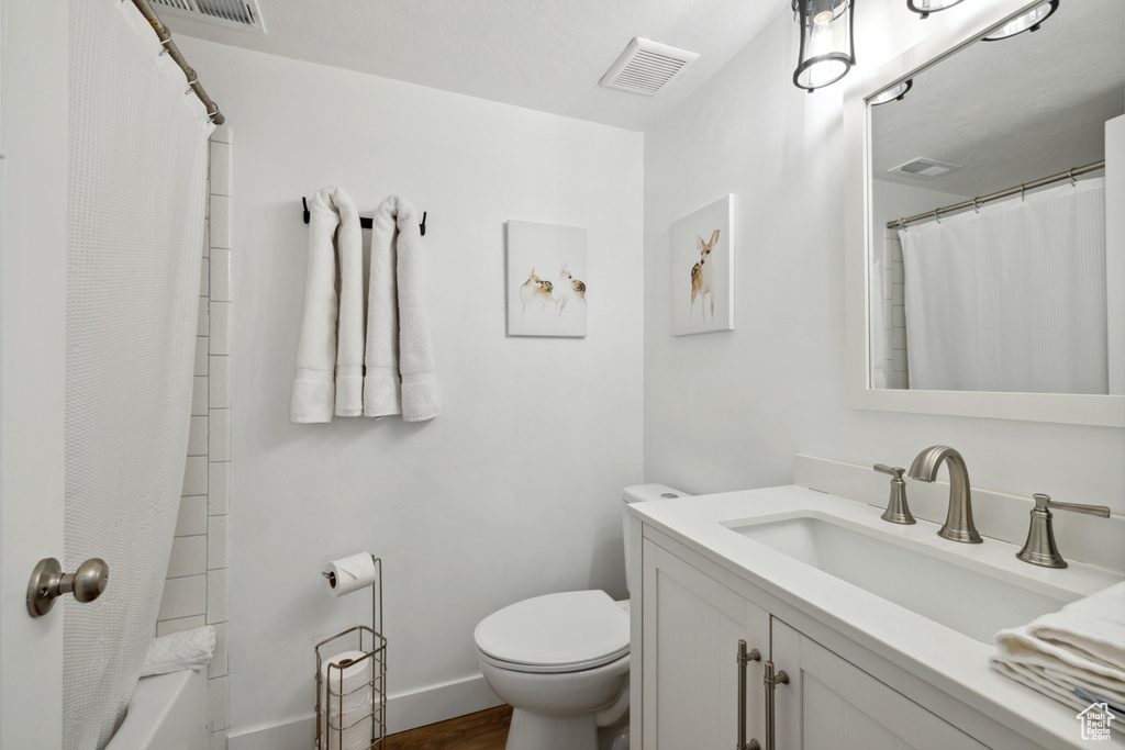 Full bath featuring vanity, toilet, wood finished floors, baseboards, and shower / bathtub combination with curtain