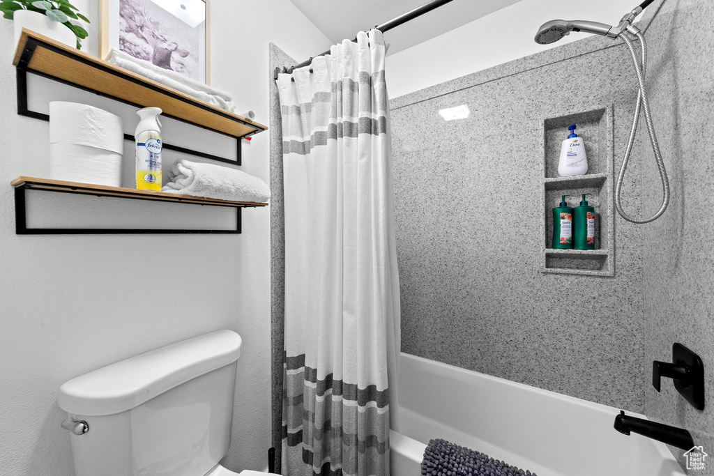 Full bathroom featuring shower / bathtub combination with curtain and toilet
