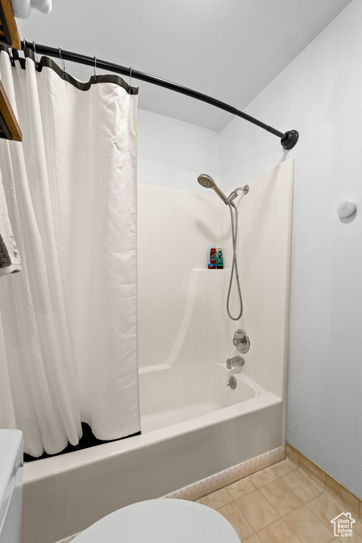 Bathroom featuring shower / bath combo, toilet, and tile patterned floors