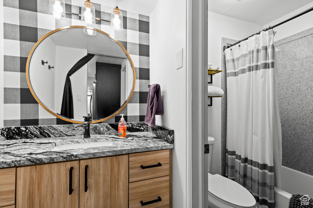 Full bathroom featuring vanity, shower / bathtub combination with curtain, and toilet