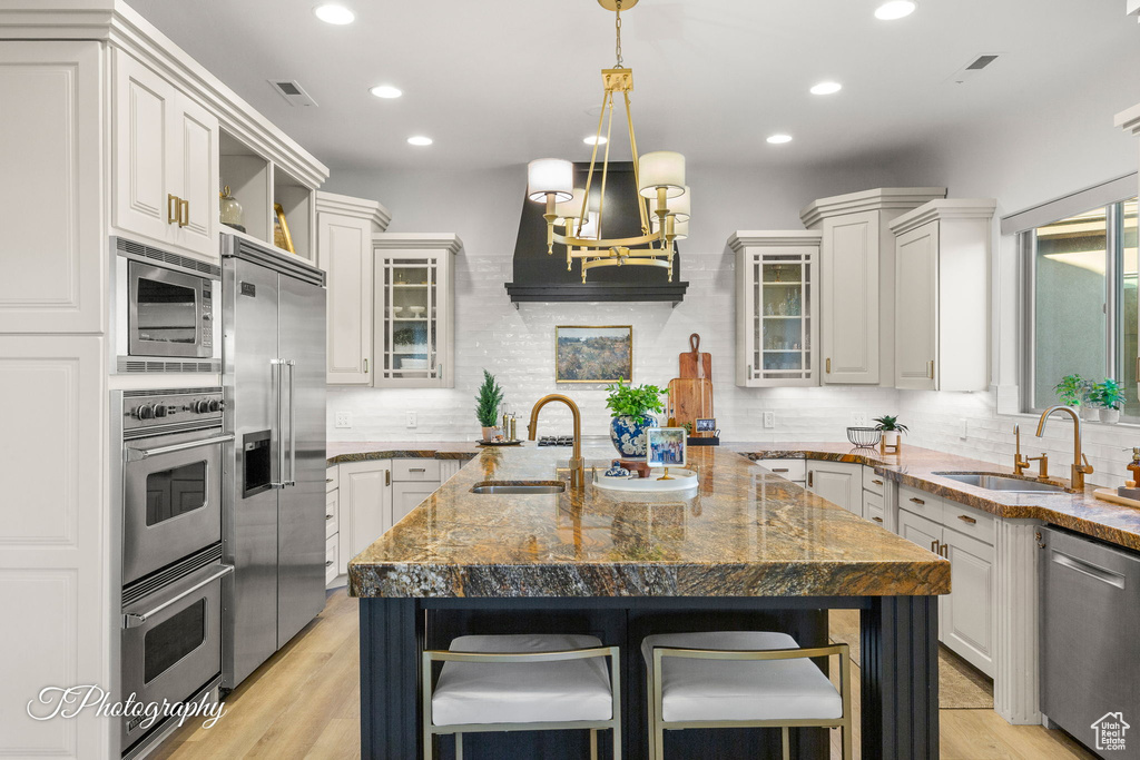 Kitchen with appliances with stainless steel finishes, a sink, an island with sink, decorative backsplash, and recessed lighting