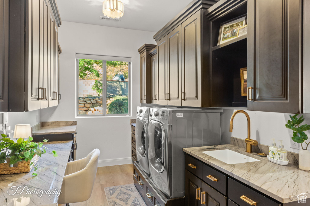 Laundry area with cabinet space, washing machine and dryer, baseboards, and light wood-style floors