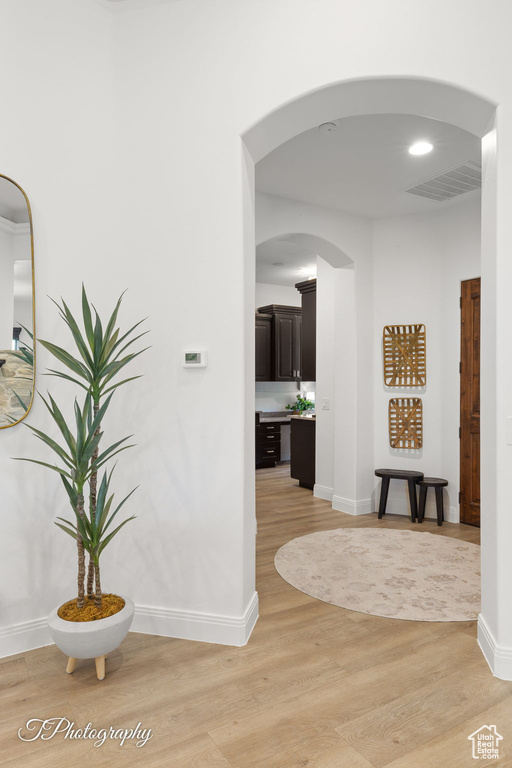 Hallway featuring light wood-type flooring, baseboards, and arched walkways