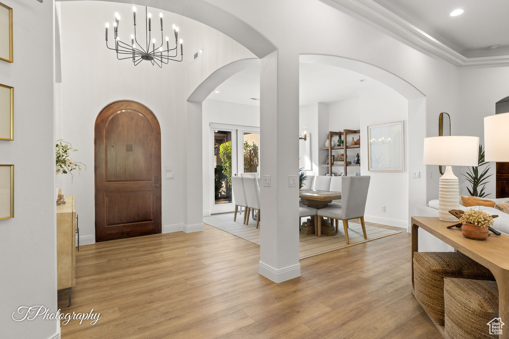 Entrance foyer with a chandelier, light wood finished floors, recessed lighting, arched walkways, and baseboards