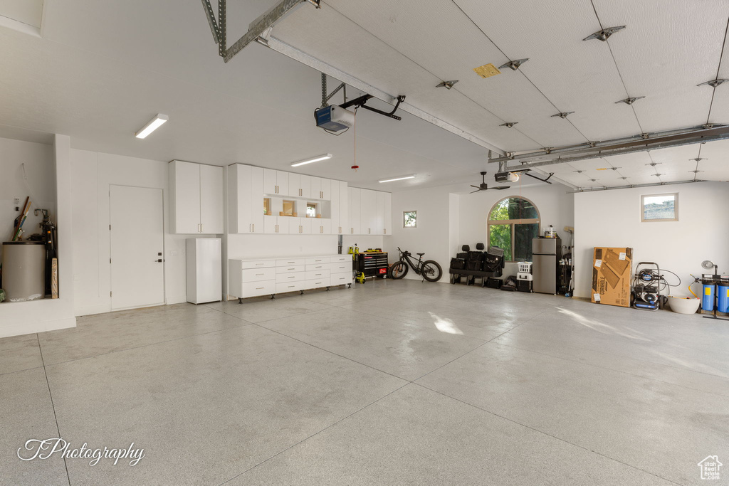 Garage featuring a garage door opener, freestanding refrigerator, and water heater