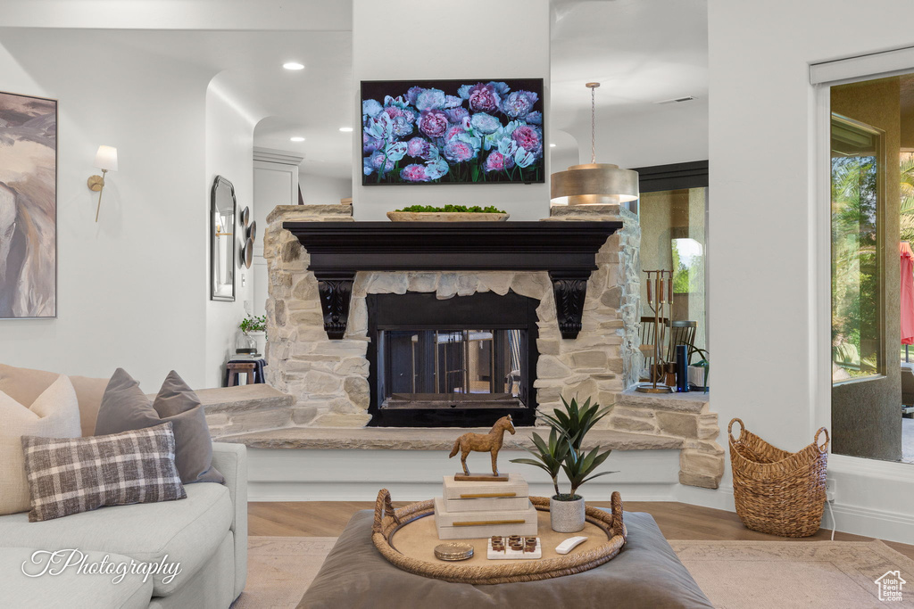 Living area featuring wood finished floors, a stone fireplace, and recessed lighting