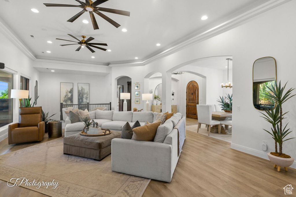 Living area featuring arched walkways, ceiling fan, light wood-style floors, ornamental molding, and recessed lighting