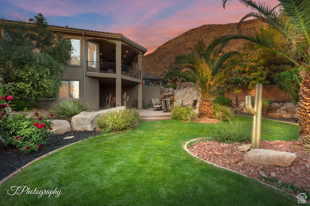 Rear view of property featuring a balcony, stucco siding, a yard, a patio area, and a mountain view