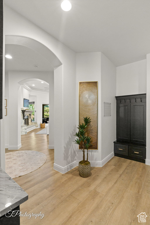 Foyer entrance with arched walkways, light wood-style flooring, and baseboards
