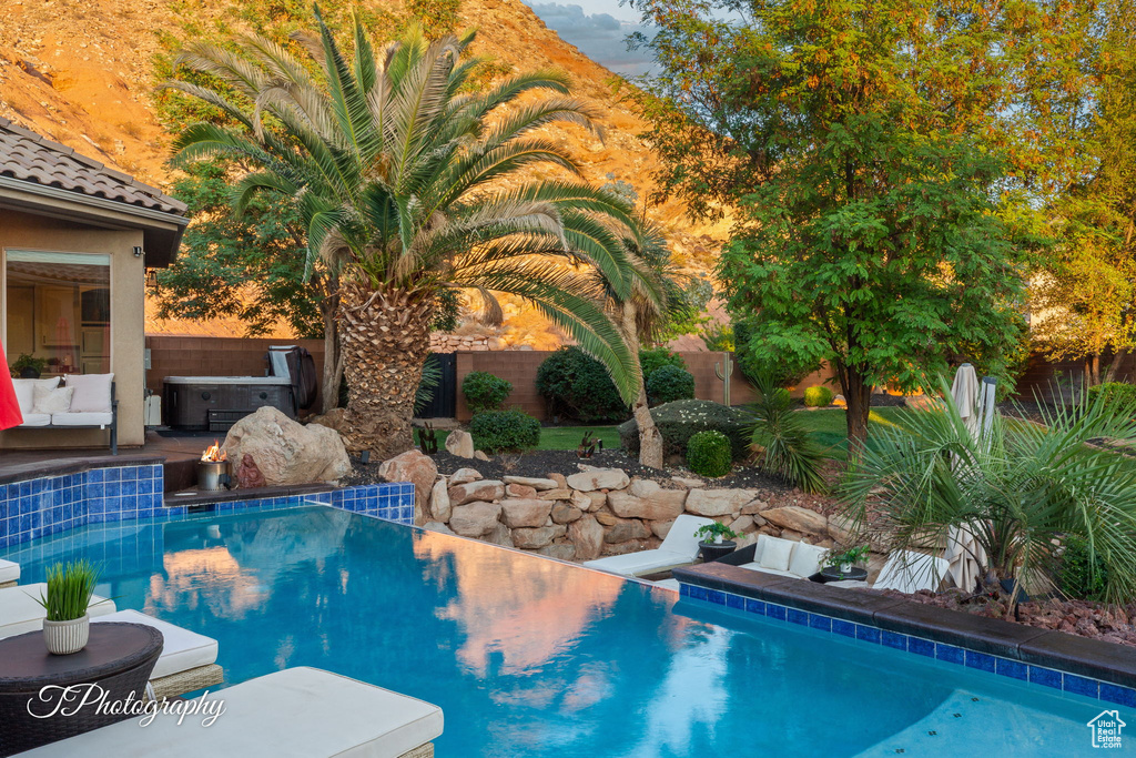 View of swimming pool featuring a hot tub and a fenced backyard