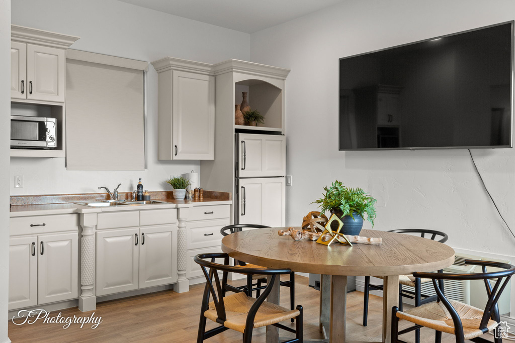 Kitchen featuring stainless steel microwave, a sink, light wood-type flooring, white cabinetry, and open shelves