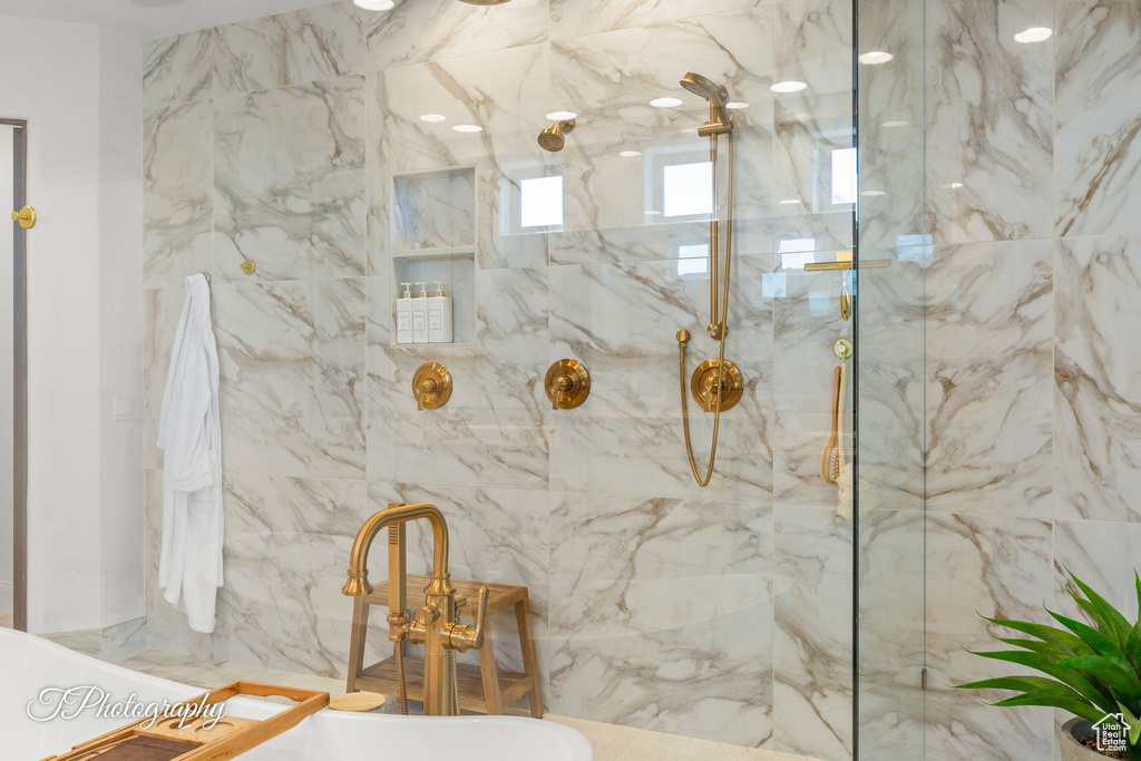 Full bath featuring a soaking tub and a marble finish shower