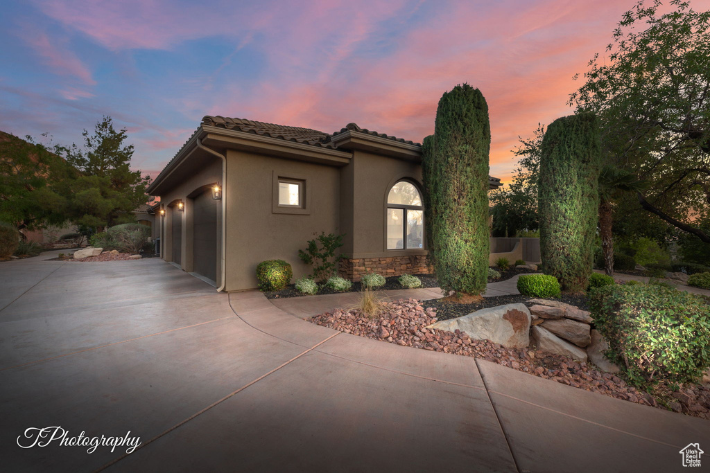 Mediterranean / spanish-style home with concrete driveway, a garage, stucco siding, stone siding, and a tile roof