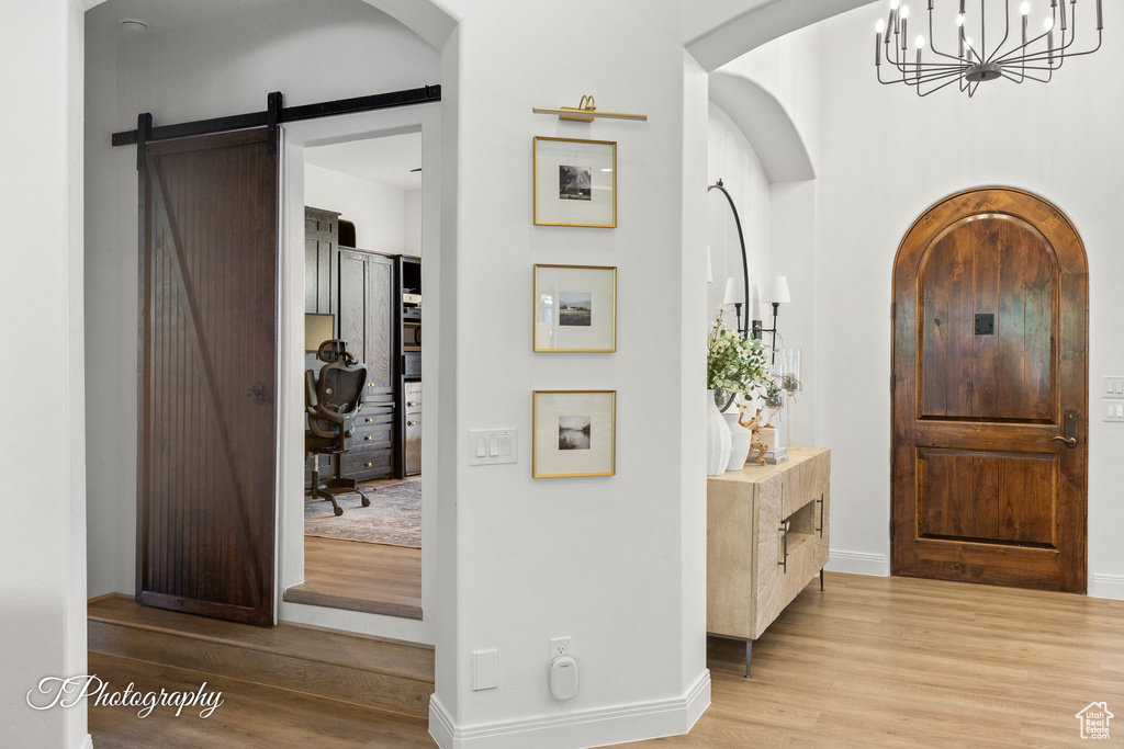 Entryway featuring wood finished floors, a chandelier, baseboards, and arched walkways