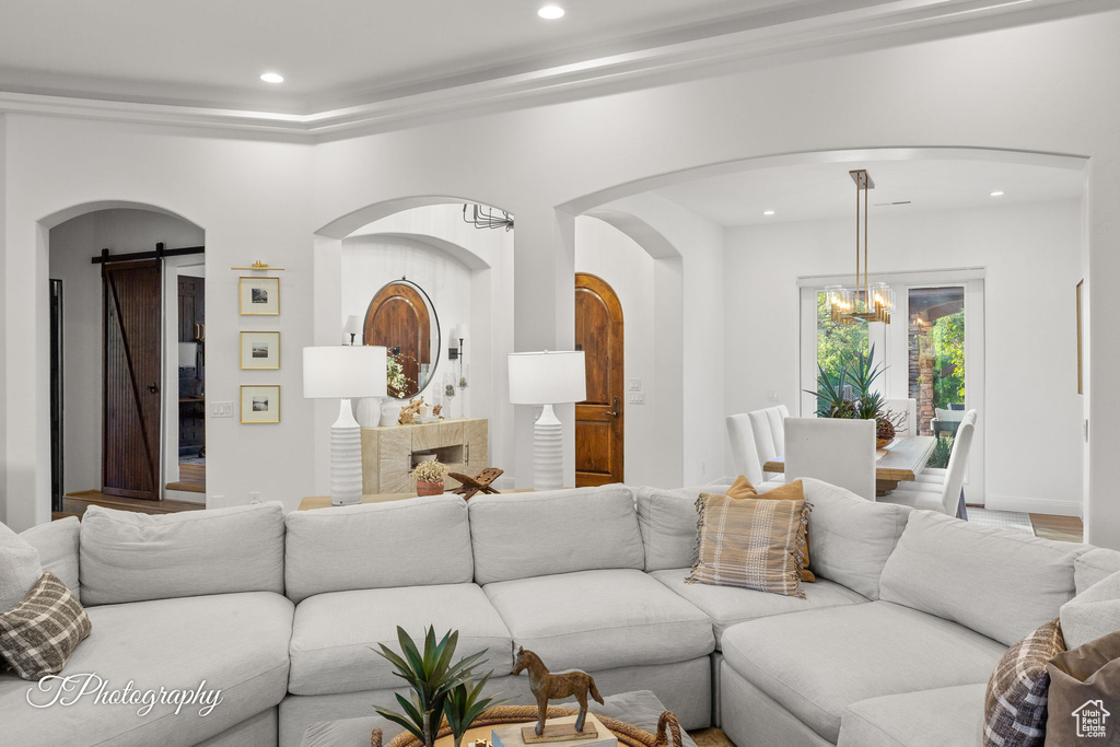 Living area with a chandelier, recessed lighting, arched walkways, and a barn door