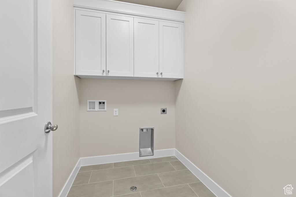 Washroom with hookup for an electric dryer, cabinet space, baseboards, and light tile patterned floors