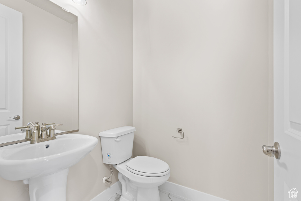 Half bath with baseboards, toilet, and a sink