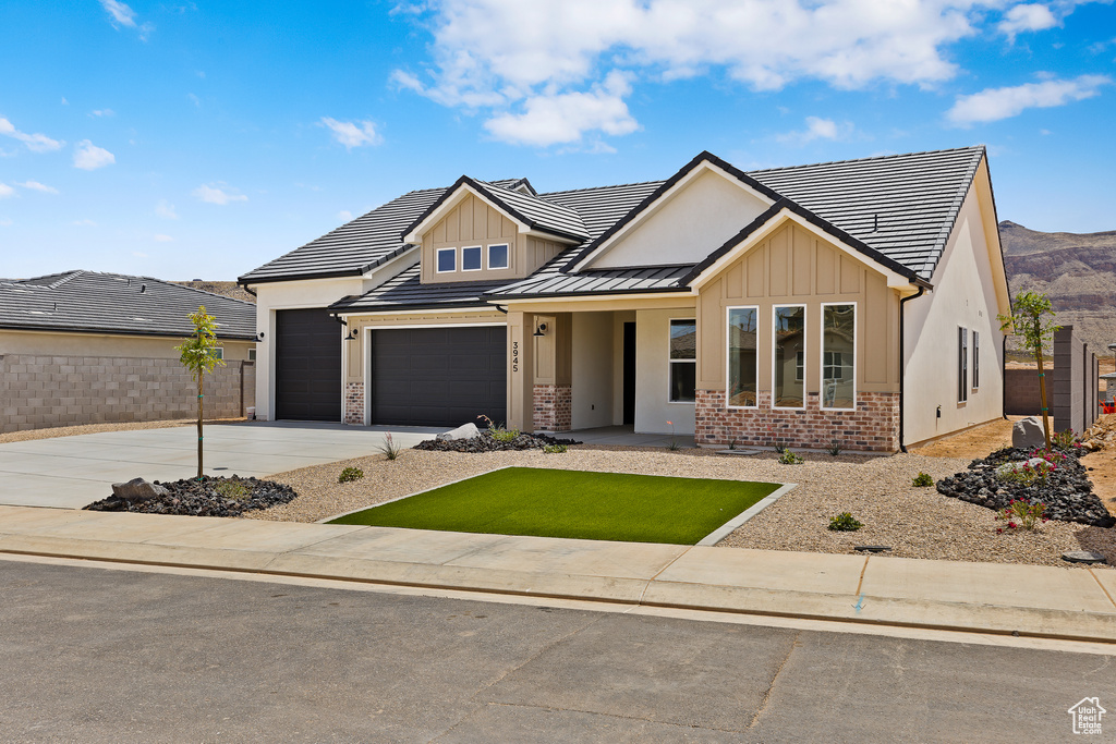 View of front facade featuring board and batten siding, concrete driveway, a garage, and brick siding