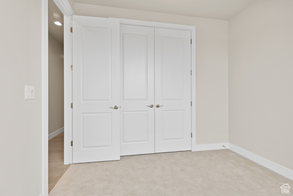 Unfurnished bedroom with baseboards, a closet, and light colored carpet