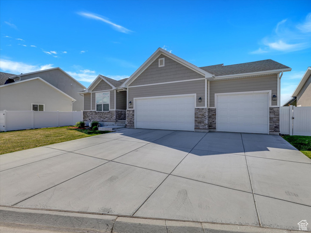 Craftsman house with a garage, driveway, and stone siding