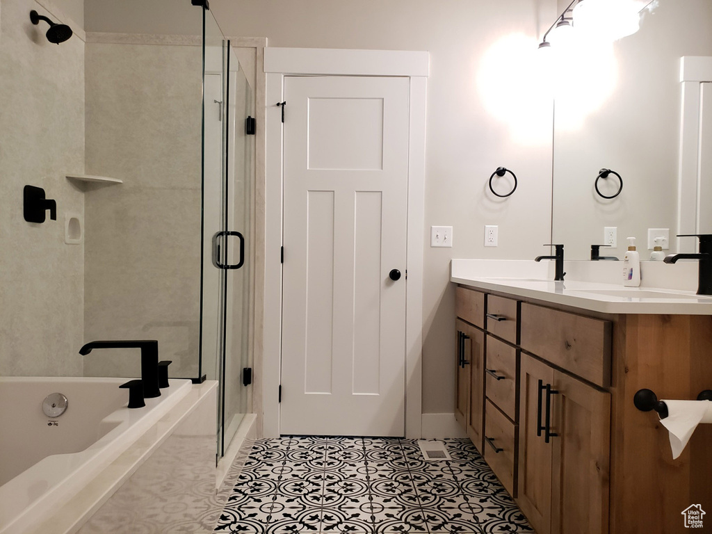 Full bathroom with double vanity, a stall shower, a bath, and baseboards