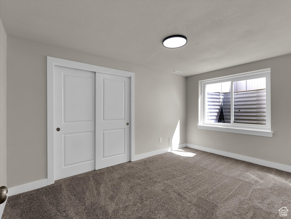 Unfurnished bedroom with carpet flooring, a closet, and baseboards