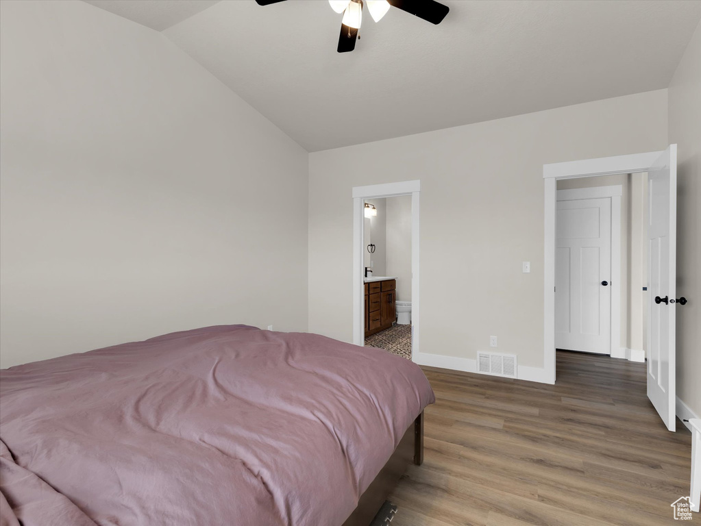 Bedroom with light wood-style flooring, lofted ceiling, baseboards, connected bathroom, and ceiling fan