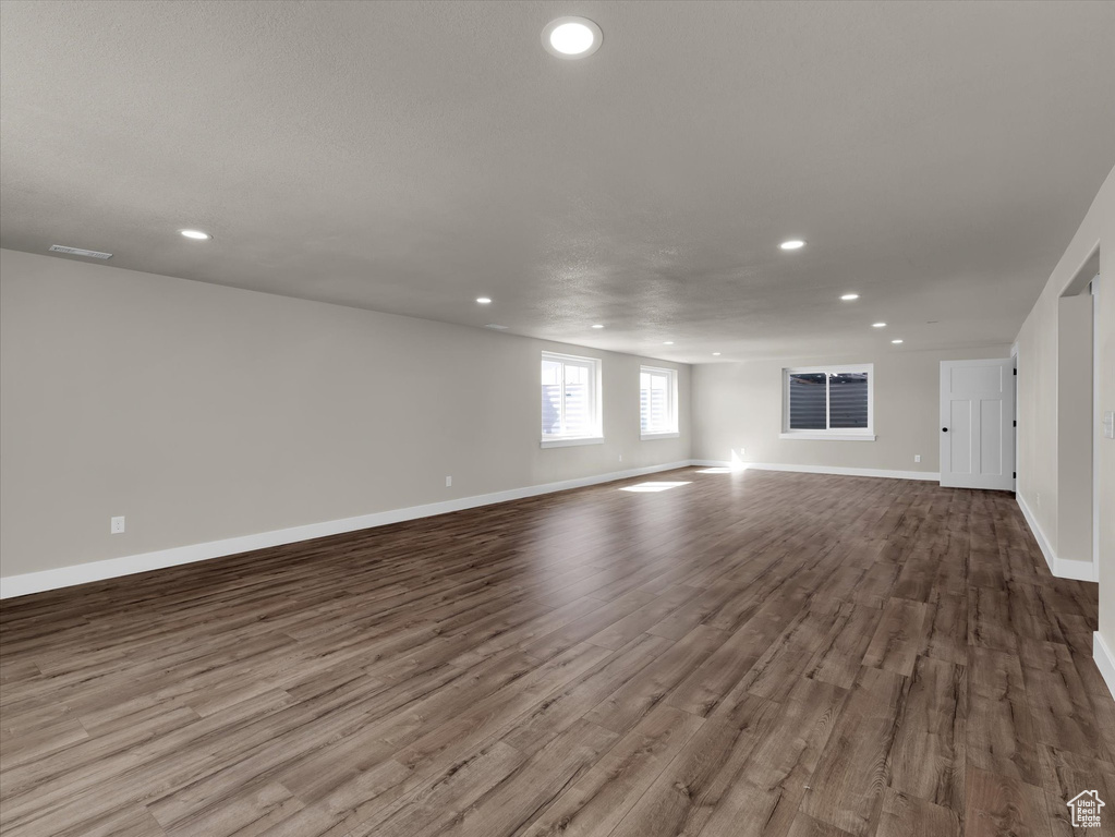 Unfurnished living room featuring dark wood finished floors, recessed lighting, and baseboards