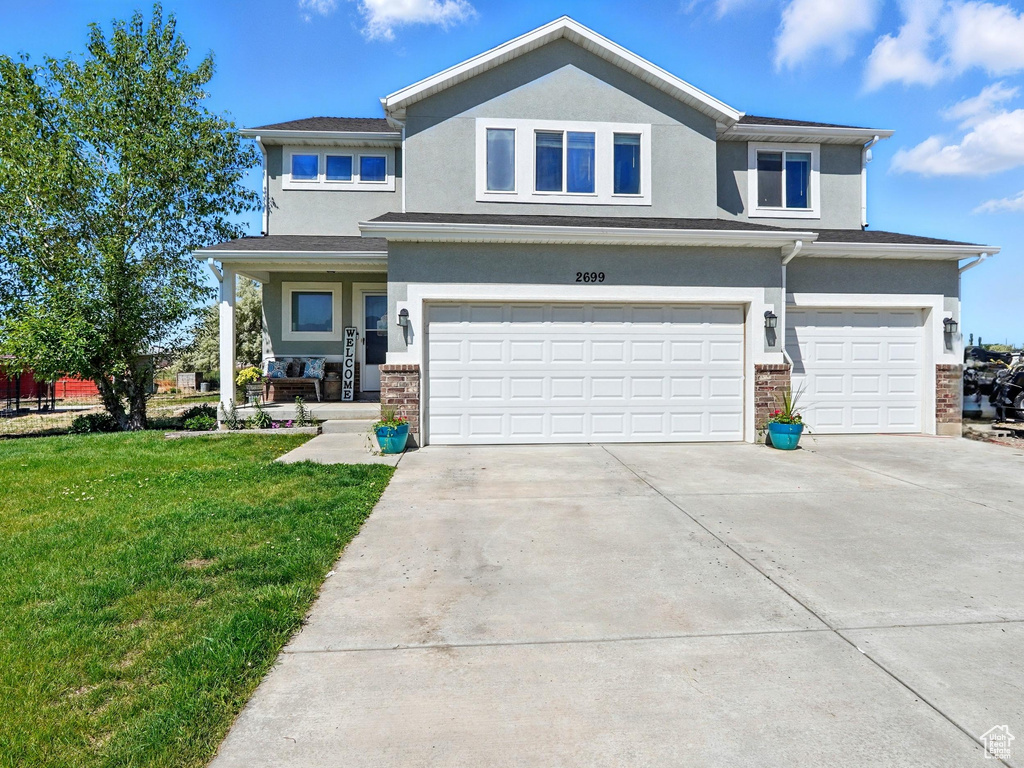 View of front facade featuring an attached garage, stucco siding, a front lawn, concrete driveway, and a porch