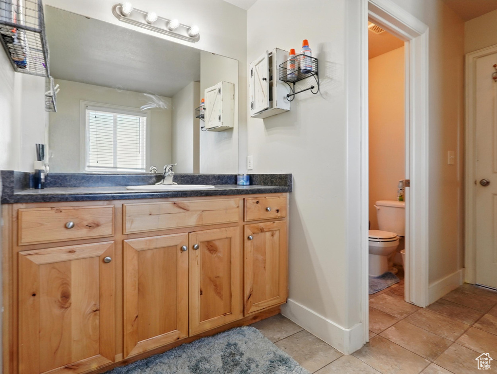 Bathroom featuring vanity, toilet, tile patterned flooring, and baseboards