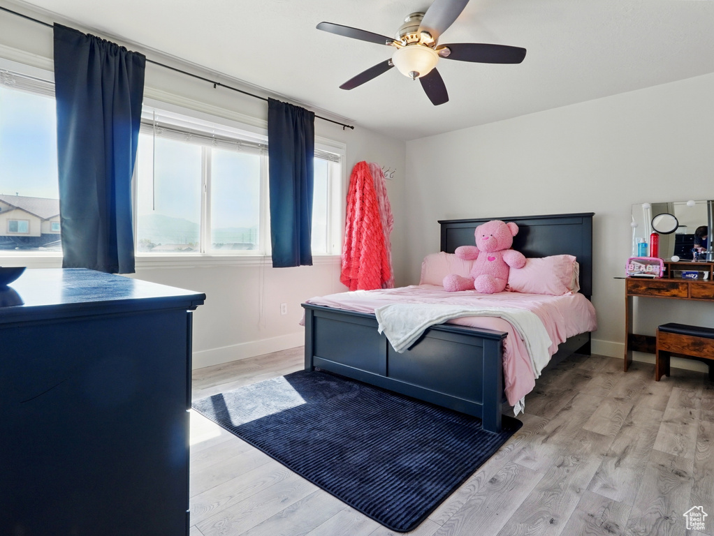 Bedroom featuring light wood finished floors, baseboards, and a ceiling fan