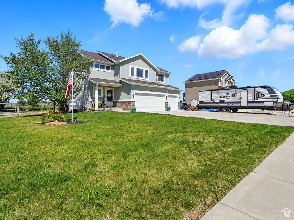 View of front of house featuring a garage, driveway, stucco siding, a front lawn, and stone siding