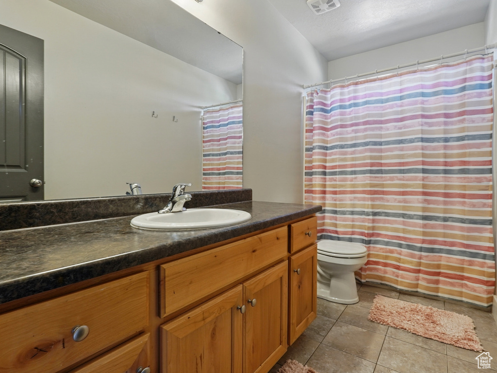 Bathroom with vanity, toilet, tile patterned flooring, and curtained shower