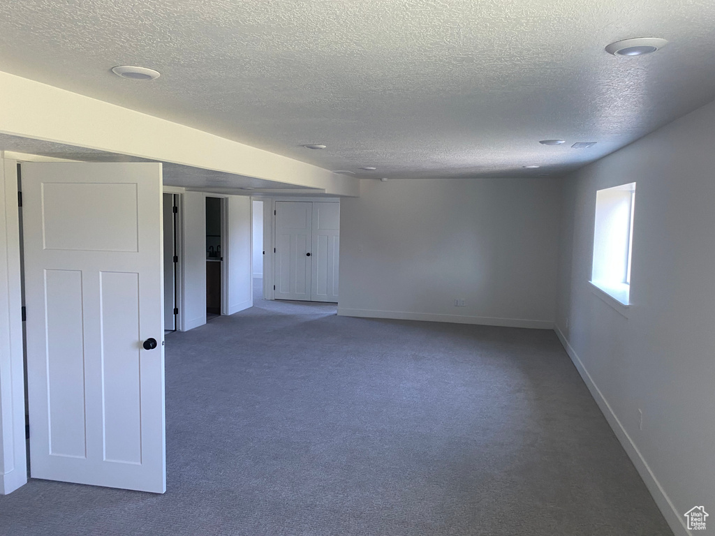 Carpeted empty room with a textured ceiling and baseboards