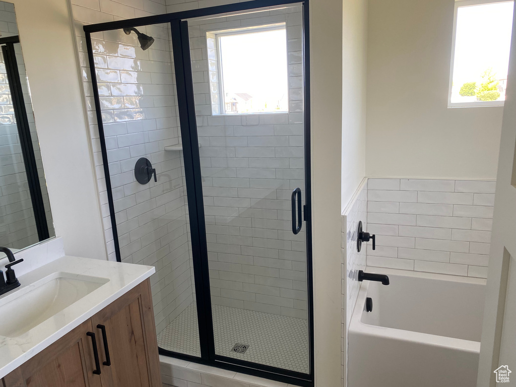 Bathroom featuring vanity, a bath, a shower stall, and plenty of natural light