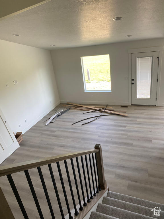 Stairway featuring wood finished floors, baseboards, a textured ceiling, and recessed lighting