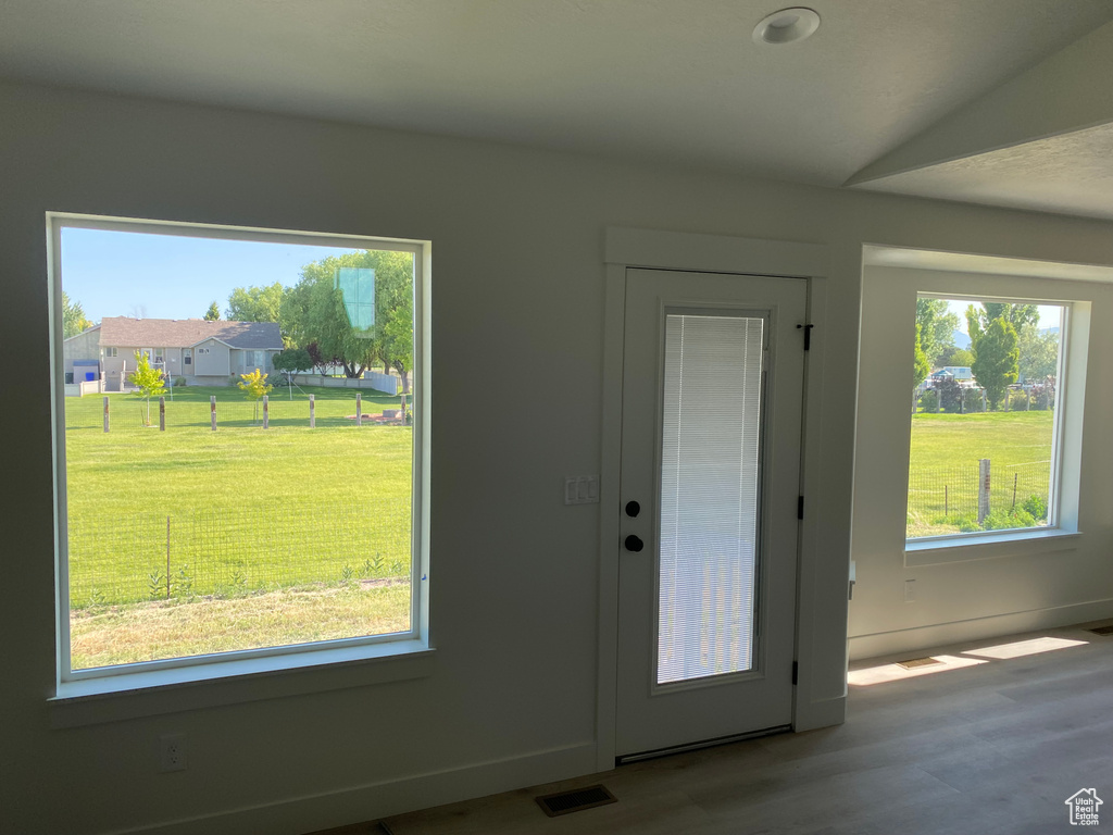 Doorway to outside with healthy amount of natural light, wood finished floors, and baseboards