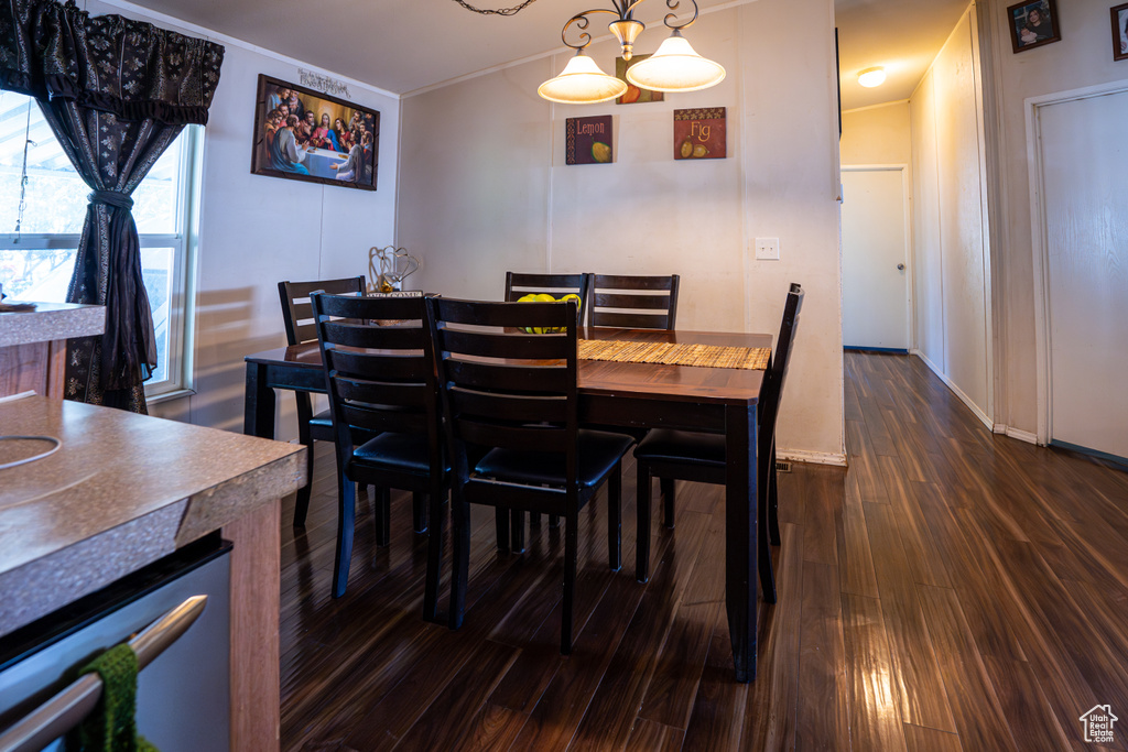 Dining area featuring dark wood-style flooring, ornamental molding, and baseboards
