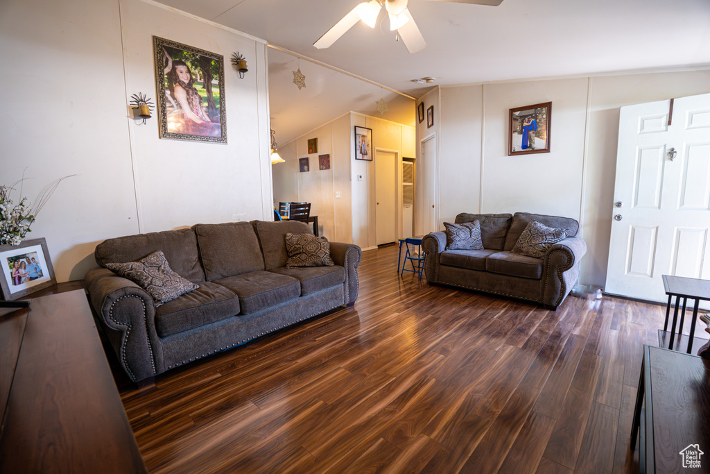 Living room with dark wood-type flooring, ceiling fan, and vaulted ceiling