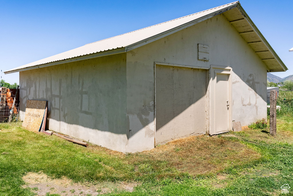 View of side of home with metal roof, an outdoor structure, and a yard