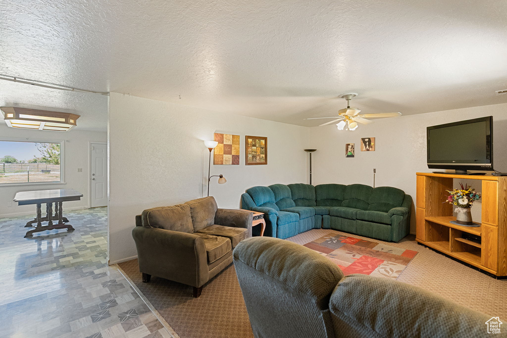 Living area featuring ceiling fan and a textured ceiling
