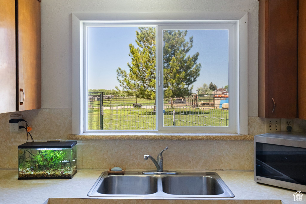Kitchen with stainless steel microwave, light countertops, a sink, and decorative backsplash
