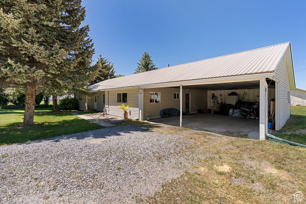 View of front of house with a front yard, metal roof, driveway, and an attached carport