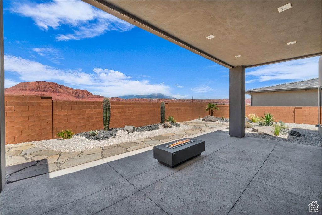 Fenced backyard with an outdoor fire pit, a patio area, and a mountain view