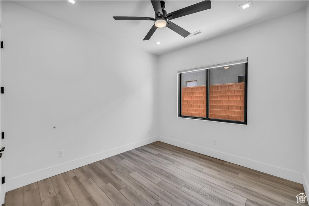 Spare room featuring wood finished floors, a ceiling fan, baseboards, and recessed lighting
