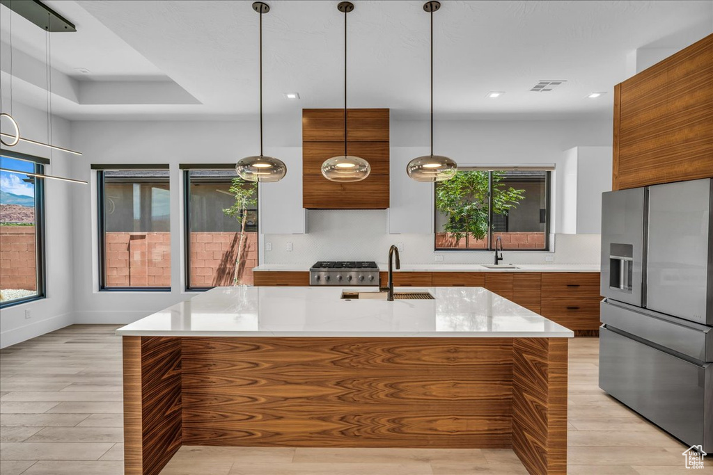 Kitchen with stainless steel fridge, modern cabinets, brown cabinets, a sink, and recessed lighting